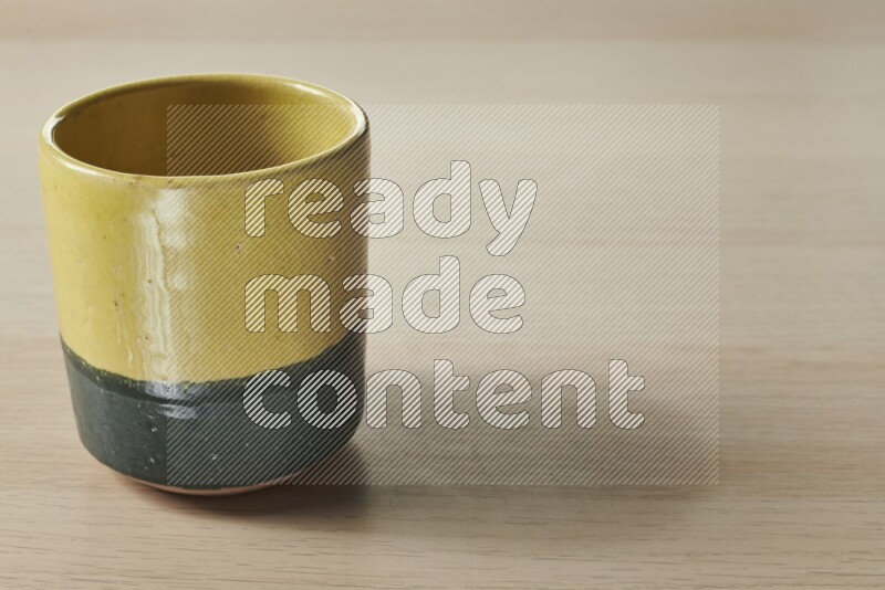 A multicolored pottery cup on light wooden background