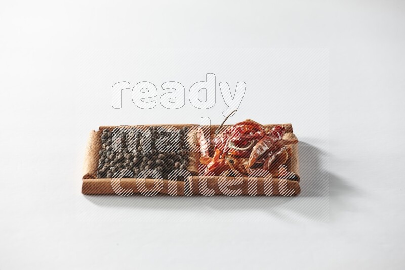 2 squares of cinnamon sticks full of red dried chilis and black pepper on white flooring