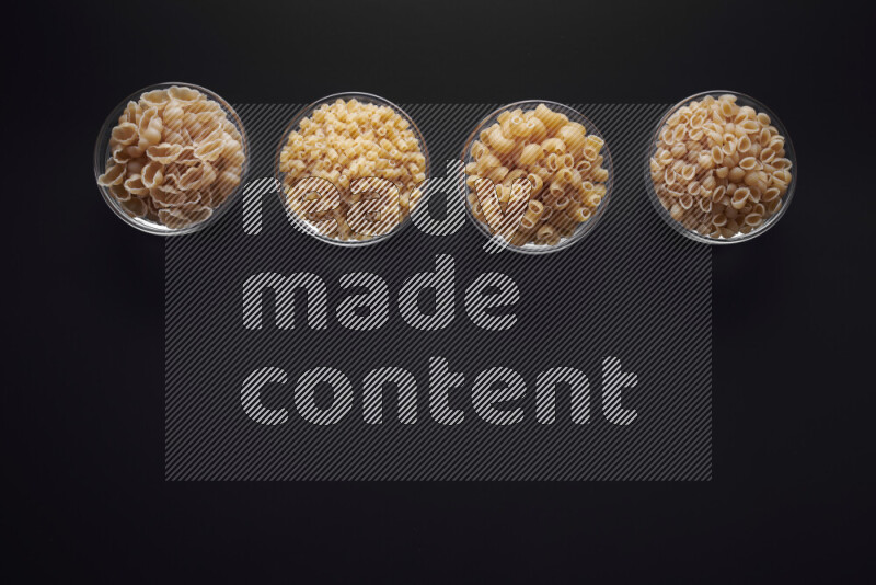 أنواع مختلفة من المعكرونة في وعاء زجاجي علي خلفية سوداء