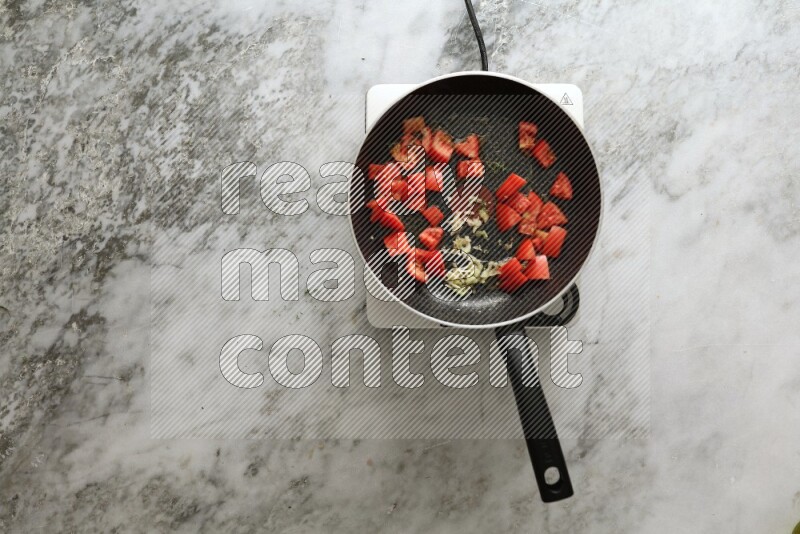 Frying pan on single electric stove on grey marble background