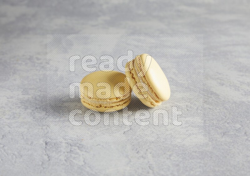 45º Shot of two Yellow Vanilla macarons  on white  marble background