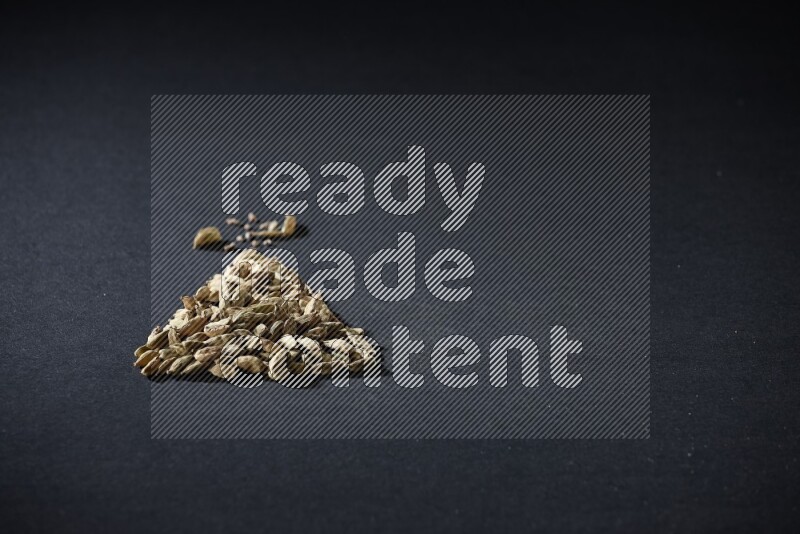 Cardamom in a triangle shape on black flooring