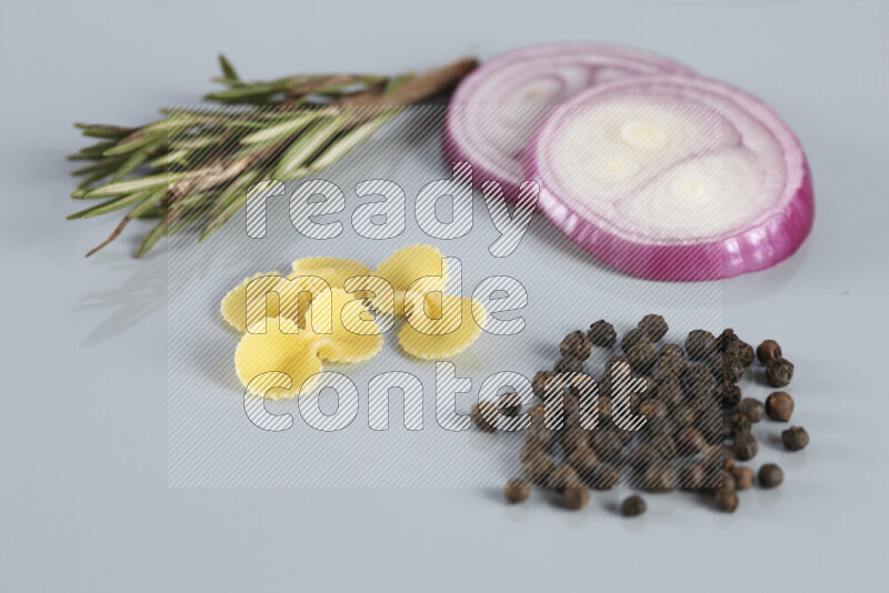 Raw pasta with different ingredients such as cherry tomatoes, garlic, onions, red chilis, black pepper, white pepper, bay laurel leaves, rosemary, cardamom and mushrooms on light blue background