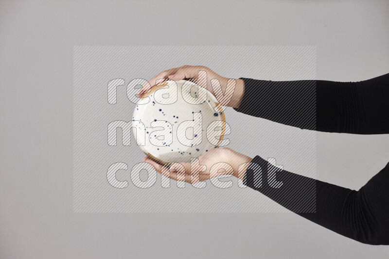 A woman in black abaya holding different pottery essentials in different positions