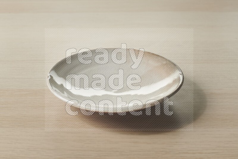 A beige pottery plate on light wooden background