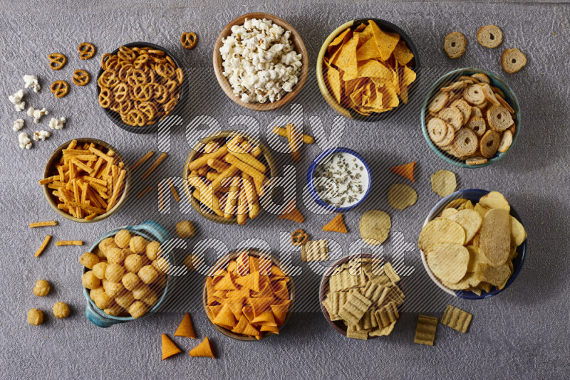 Assorted snacks in pottery bowls on grey background