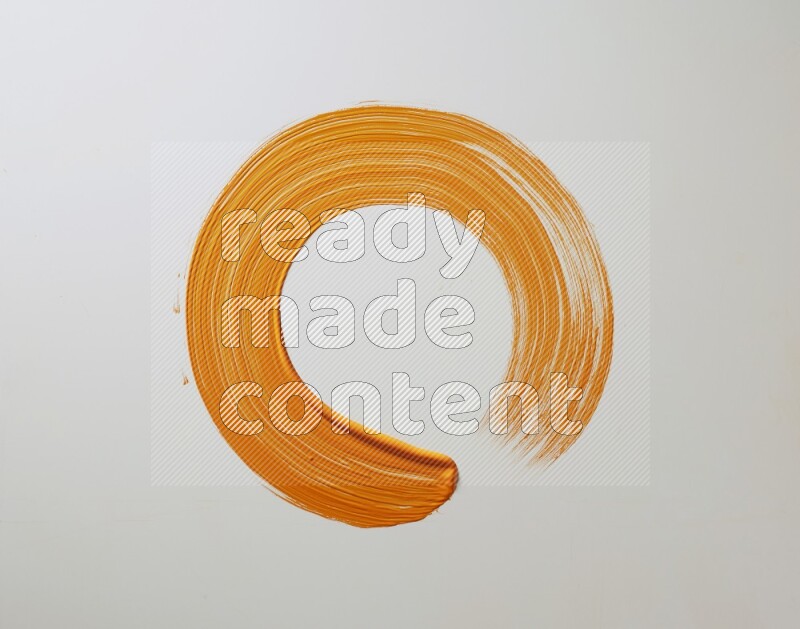 An orange circular painting brush stroke on white background
