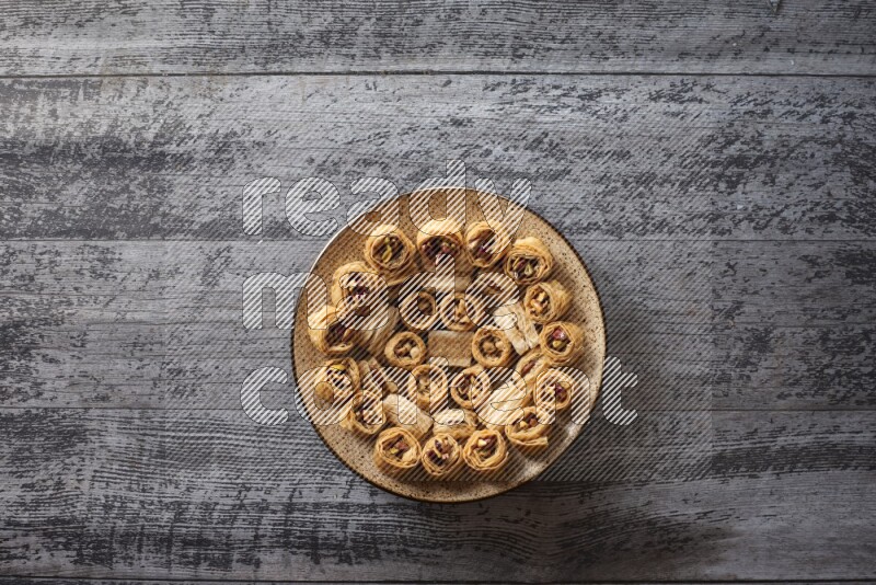 حلويات شرقية في صحن فخاري مع المكسرات والقهوة والعسل علي خلفية خشبية