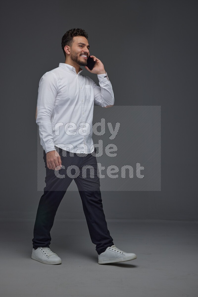 A man wearing smart casual talking in the phone eye level on a gray background