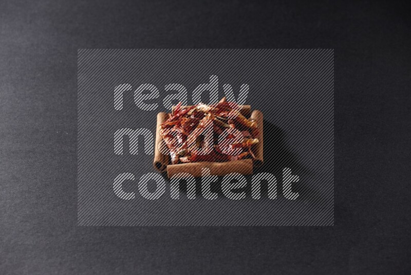 A single square of cinnamon sticks full of chilis on black flooring
