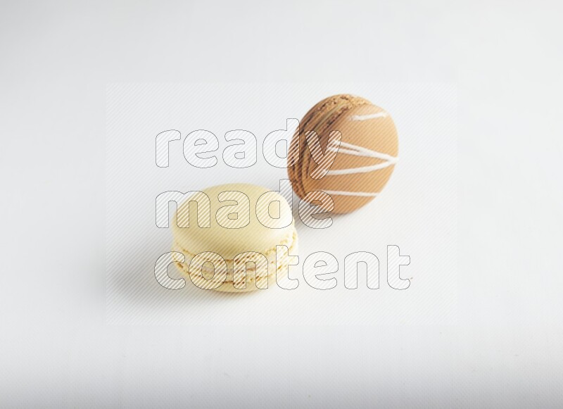 45º Shot of of two assorted Brown Irish Cream, and Yellow Vanilla macarons on white background