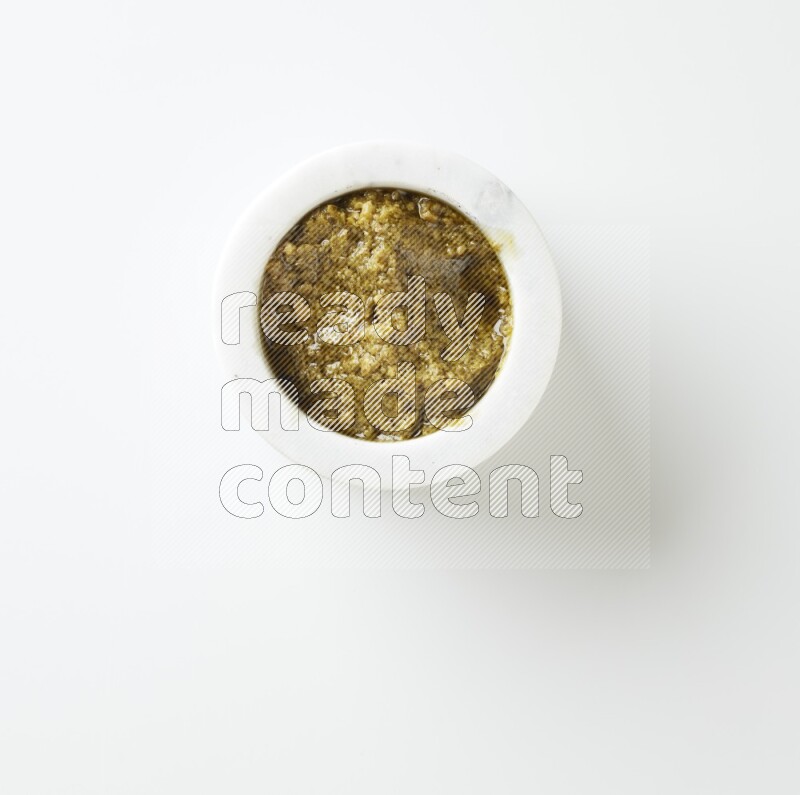 small white ceramic round bowl filled with pesto paste on a white counter top