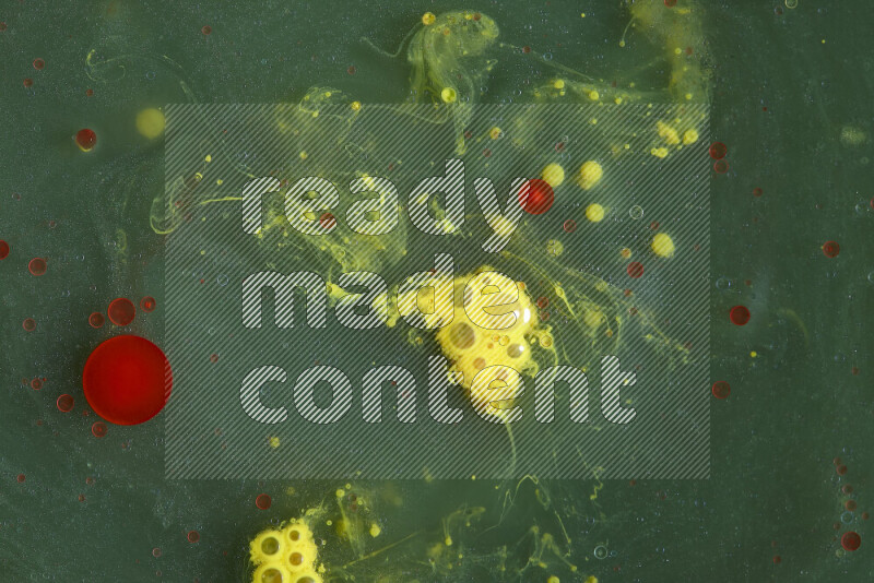 The image captures a dramatic splatter of red, green and yellow paints over the backdrop