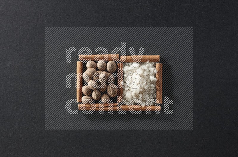 2 squares of cinnamon sticks full of nutmeg and white salt on black flooring
