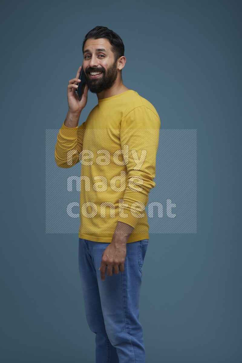 A man having a calling in a blue background wearing a yellow shirt