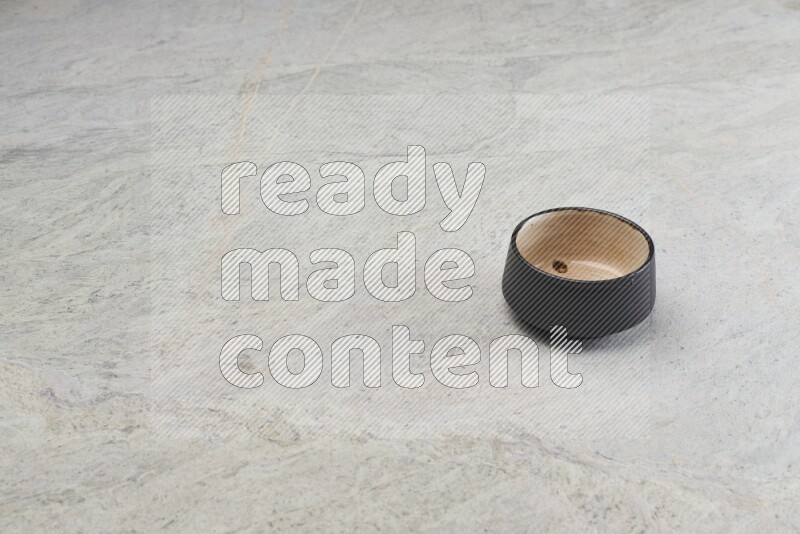 A black pottery bowl on grey marble background