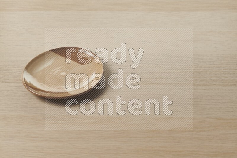 A multicolored pottery plate on light wooden background