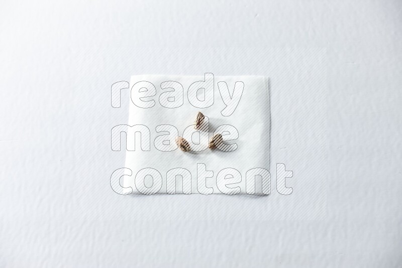 3 حبات من الفستق المقشر على قطعة من الورق على خلفية بيضاء