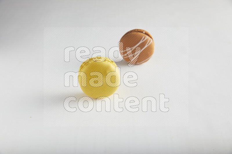 45º Shot of of two assorted Brown Irish Cream, and Yellow Lemon macarons on white background