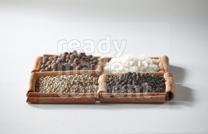 4 squares of cinnamon sticks full of allspice, white salt, white pepper and black pepper on white flooring