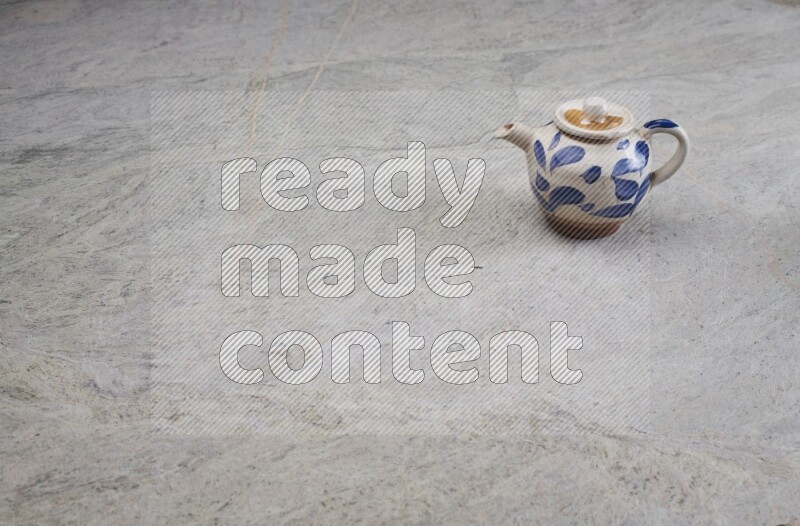 A pottery teapot on grey marble background