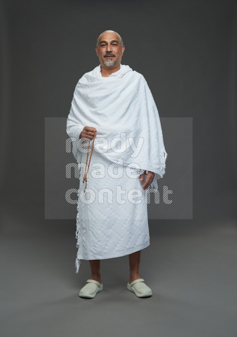 A man wearing Ehram Standing holding rosary on gray background