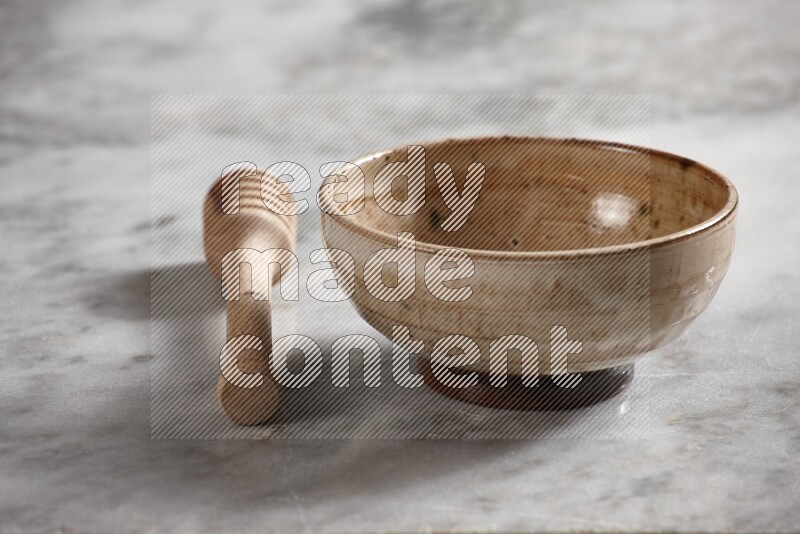 Beige pottery bowl with wooden honey dipper on the side on grey marble background