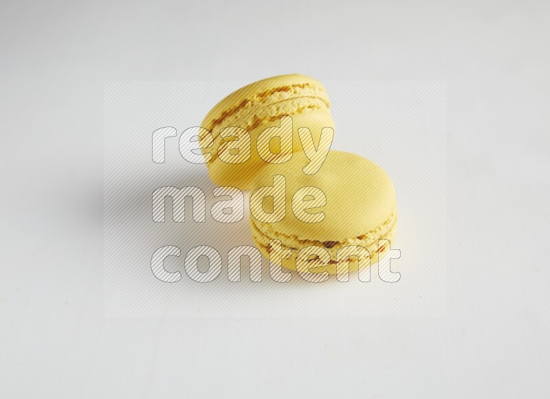 45º Shot of two Yellow Lemon macarons on white background