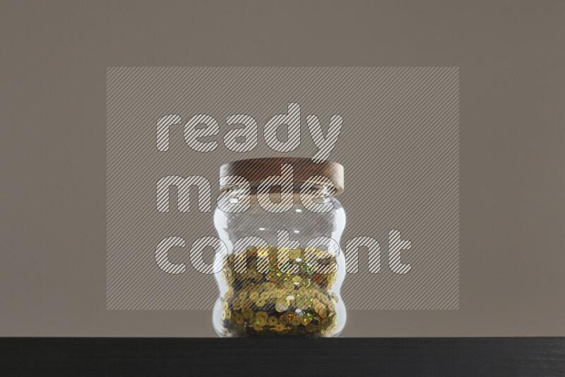 Sequins in a glass jar on black background