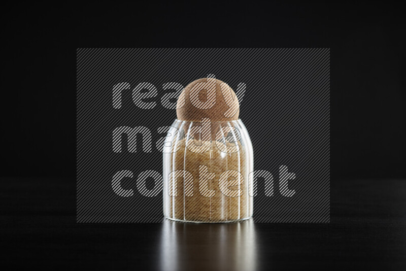 Basmati golden rice in a glass jar on black background
