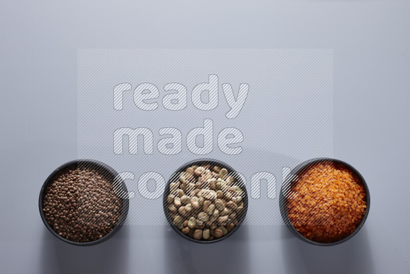 Legumes in pottery bowls on light grey background