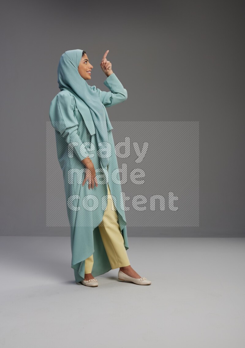 Saudi Woman wearing Abaya standing interacting with the camera on Gray background