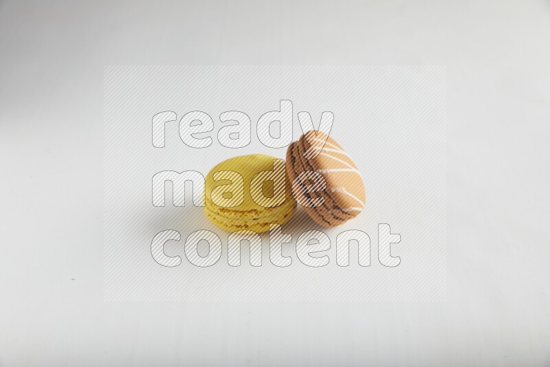 45º Shot of of two assorted Brown Irish Cream, and Yellow Lemon macarons on white background