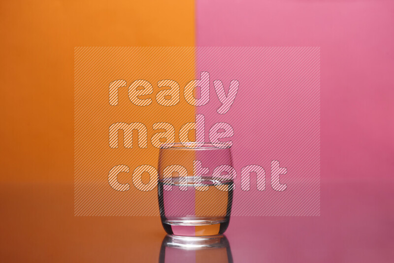 The image features a clear glassware filled with water, set against orange and pink background