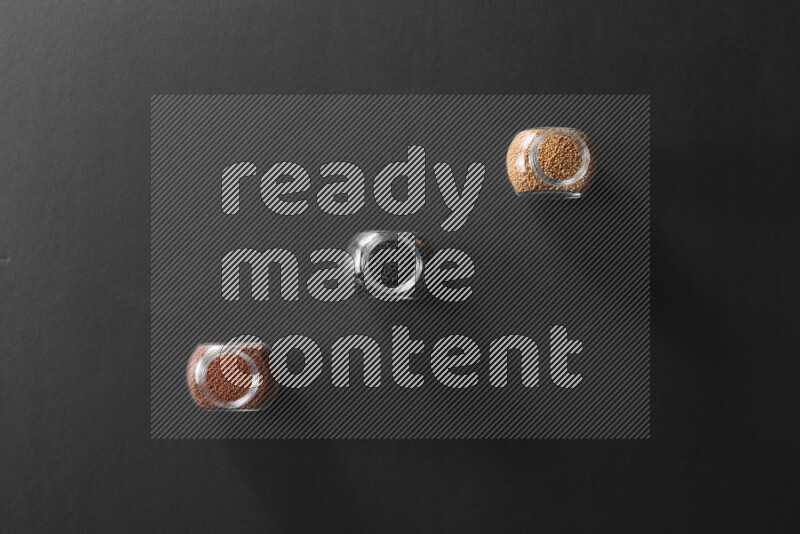 3 glass spice jars full of black seeds, mustard seeds and garden cress on black flooring