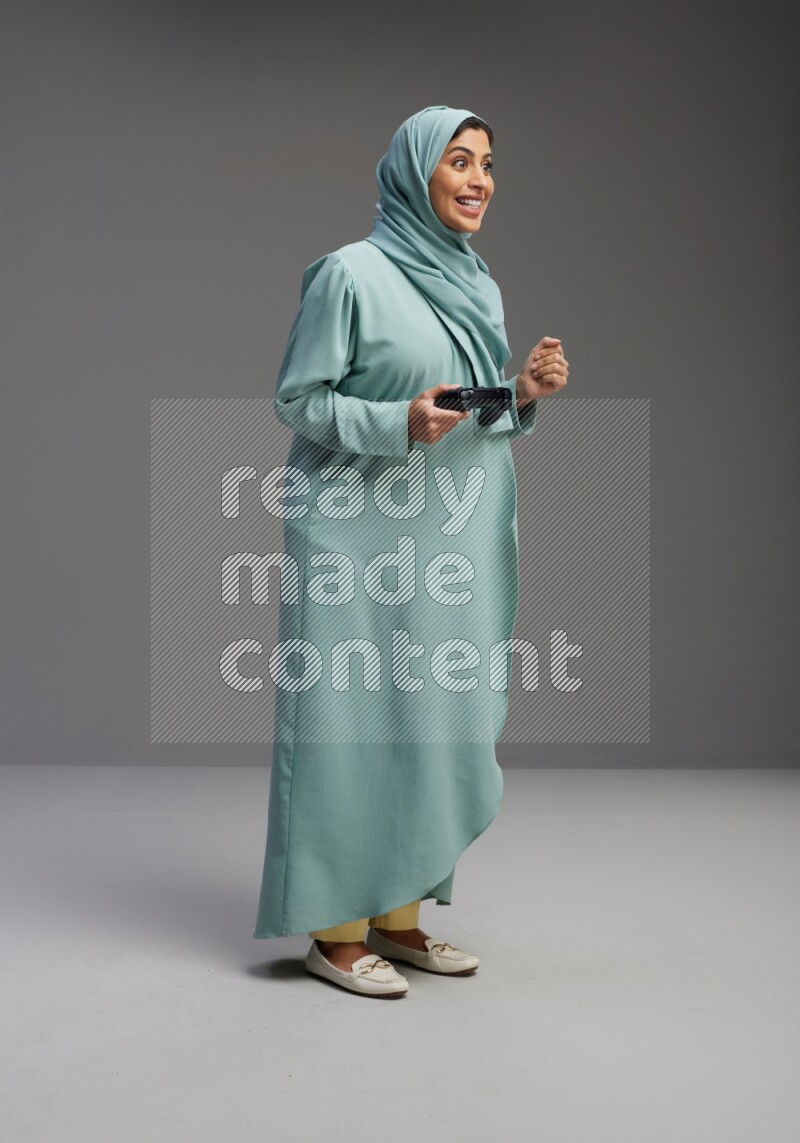 Saudi Woman wearing Abaya standing Playing Games on Gray background