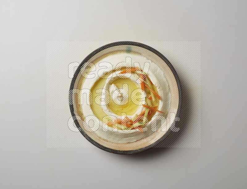 Lebnah garnished with sliced carrots &cucumber in a pottery plate on a white background