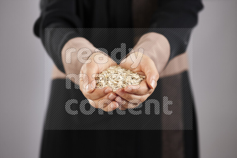 Woman in abaya holding different kinds of legumes in different positions
