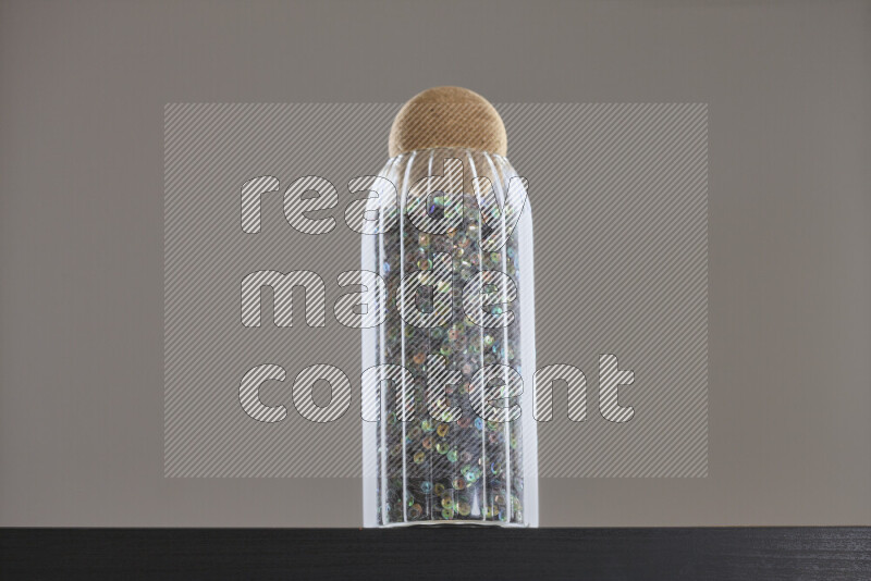 Sequins in a glass jar on black background