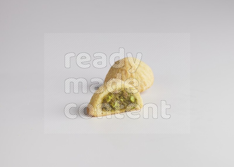 Two Pieces of Maamoul filled with pistachio paste  one of them is cut direct on white background