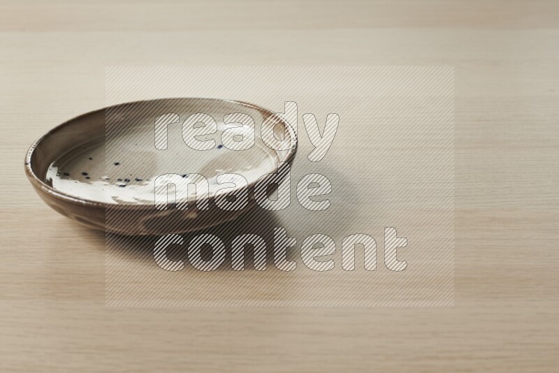 A multicolored pottery plate on light wooden background