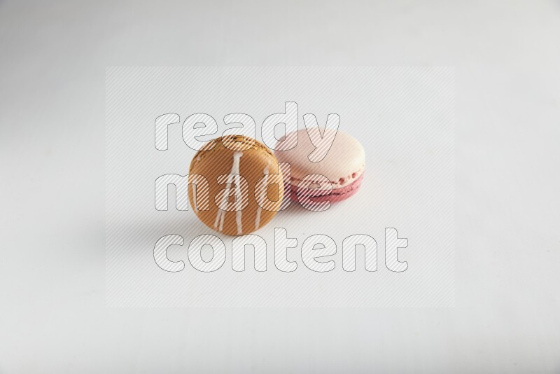 45º Shot of of two assorted Brown Irish Cream, and Pink Litchi Raspberry macarons on white background