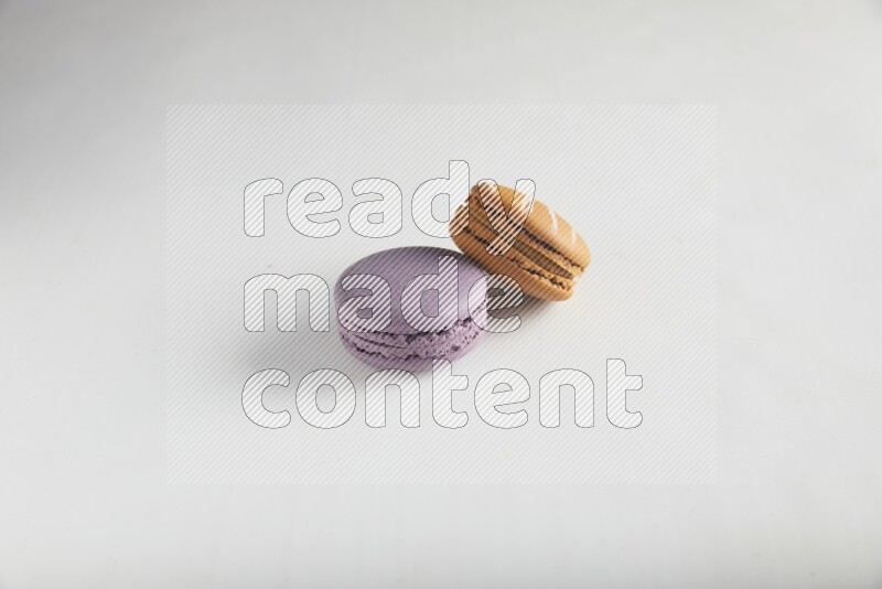 45º Shot of of two assorted Brown Irish Cream, and Purple Blueberry macarons on white background