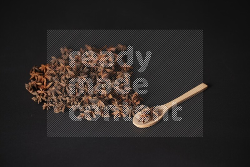 Star Anise in a wooden spoon and spreading on a black flooring