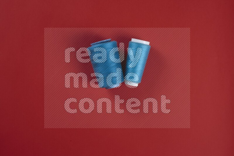 A blue and red collection of sewing and tailoring tools arranged on a red background