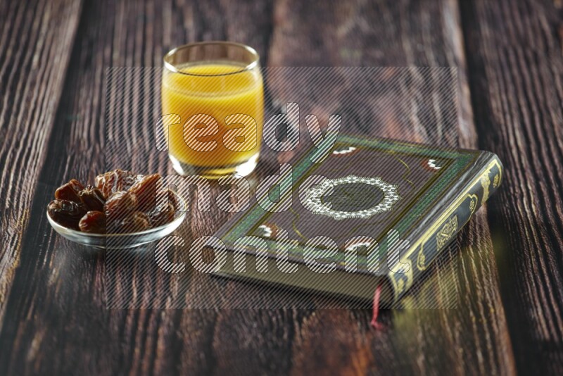 Quran with dates, prayer beads and different drinks all placed on wooden background
