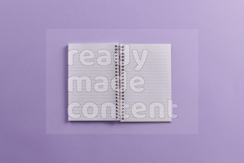 A blank open notebook with school supplies on purple background