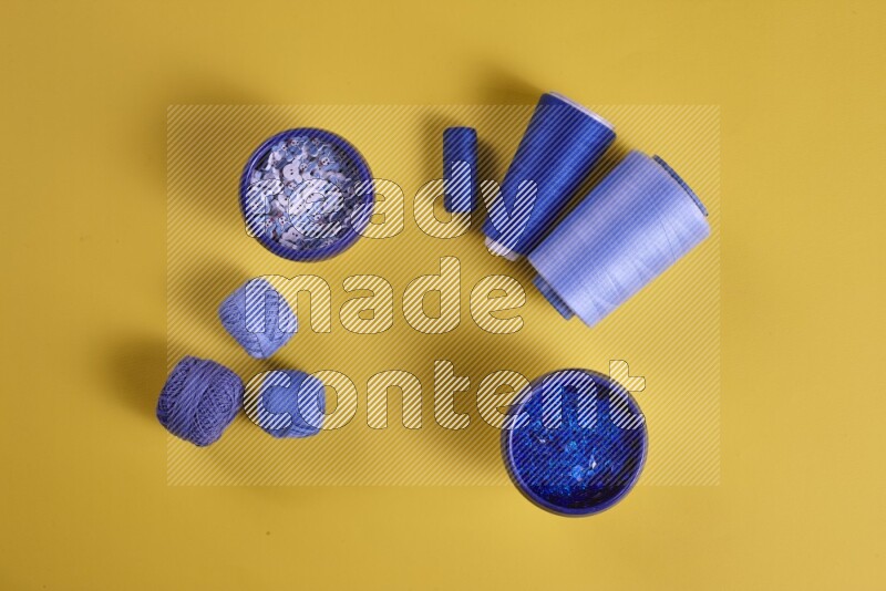 مجموعة من أدوات الخياطة والتفصيل زرقاء اللون على خلفية صفراء