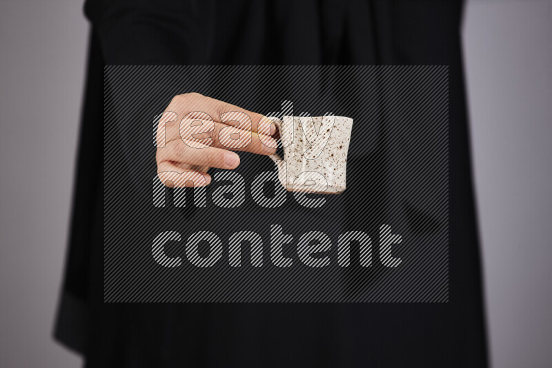 A woman in black abaya holding different pottery essentials in different positions