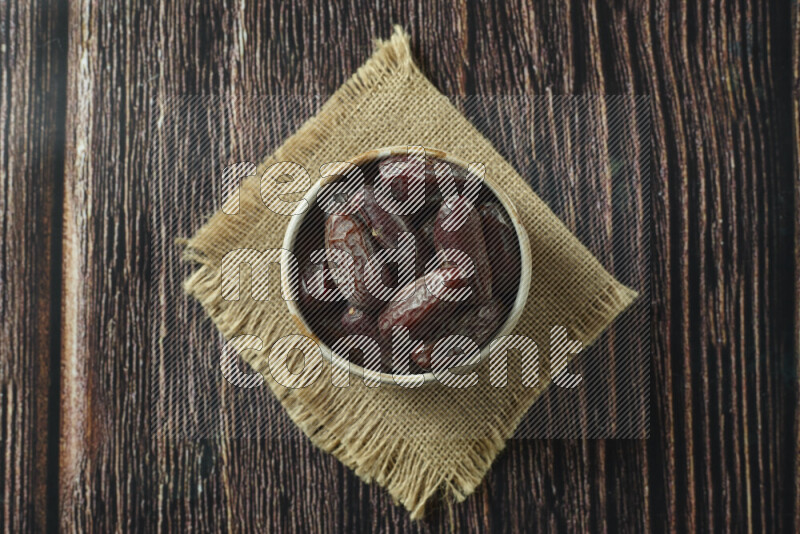 Dates in different bowls (wooden, pottery and glass) on wooden background